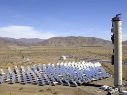 Foto: Inmitten einer kargen Wüstenlandschaft steht ein Array aus etwa hundert gleichgroßen, mehr als Mannshohen Spiegeln, die alle zu einem hohen Turm hin ausgerichtet sind.