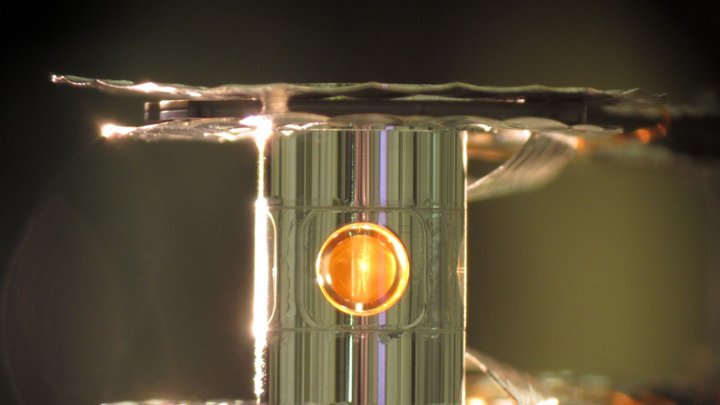 Ausschnitt des transparenten Zielzylinders. Im Inneren des Zylinders befindet sich ein goldfarbener, kugelförmiger Hohlraum.