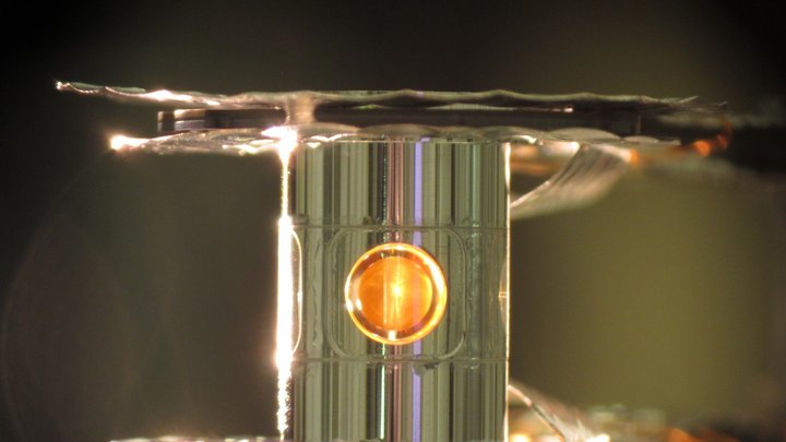 Ausschnitt des transparenten Zielzylinders. Im Inneren des Zylinders befindet sich ein goldfarbener, kugelförmiger Hohlraum.