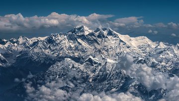 Schneebedecktes Gebirgsmassiv mit zahlreichen Gipfeln, umgeben von Wolken