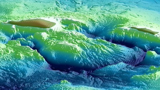 Am Computer erstelltes Bild des Vulkans Kikai: Verschiedene Grüntöne geben die Erhebung eines Berges unter Wasser an. An seiner Spitze zeigt sich ein braunes Loch, das die Caldera anzeigt.