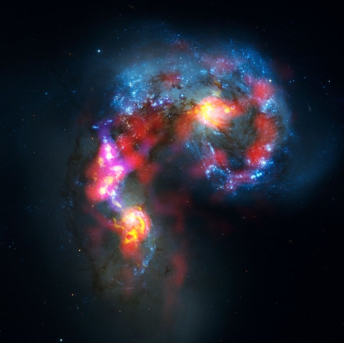 Antennengalaxie Vor einem schwarzen Hintergrund ist eine bunte, leuchtende Galaxie abgebildet.