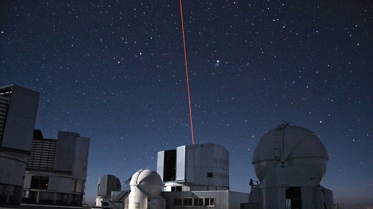 Gebäude in der Dämmerung. Aus einem Dach kommt ein roter Laserstrahl.