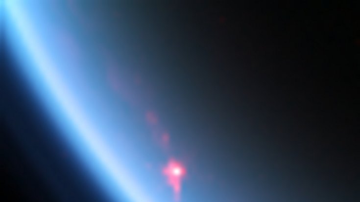 Teil eines Himmelskörpers mit Atmosphäre, darauf ein kleiner heller Fleck.