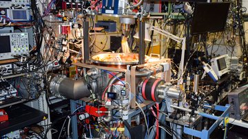 Experimentaufbau mit zahlreichen Metallrohren, Experimentierkammern, Kabeln und Messgeräten im Labor