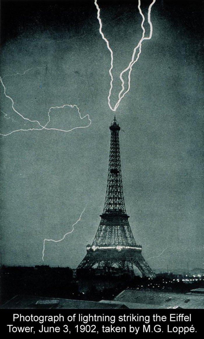 Schwarzweiss-Fotographie: der Eiffelturm in Paris bei Nacht, Blitzeinschlag von oben in den Eiffelturm.