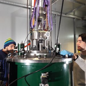 Zwei Forscher arbeiten an einem zylinderförmigen Instrument.