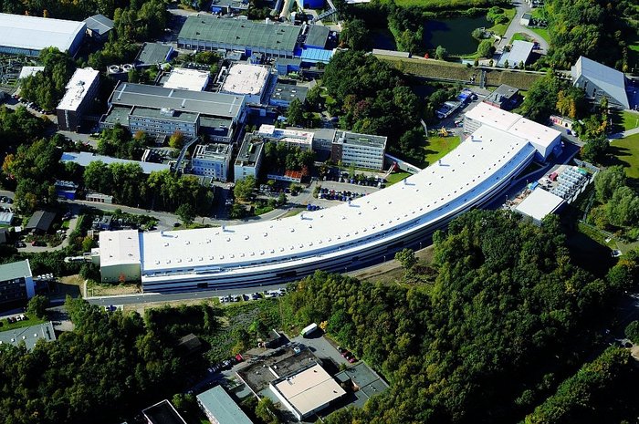 Luftbild der knapp 300 Meter langen Experimentierhalle von PETRA III wenige Monate nach der Fertigstellung, im Oktober 2008. Der Boden der Halle wurde in Form einer einzigen, ein Meter dicken Betonplatte gegossen, die den Beschleuniger und die Experimente trägt. Es ist die wahrscheinlich längste in einem Stück gefertigte Betonplatte der Welt.