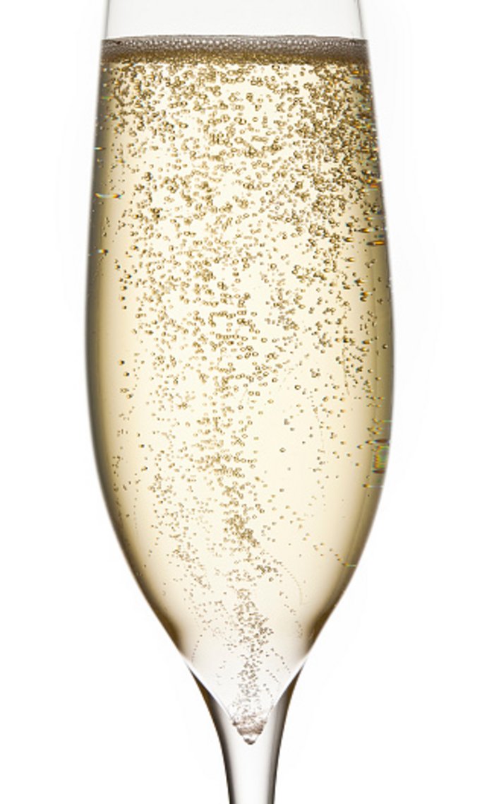 Perlender Champagner im Glas Glas mit heller Flüssigkeit, die Bläschen bildet.