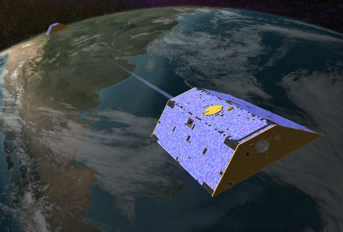 Satellitenduo GRACE Computergrafik. Vor dem Hintergrund der Erde fliegt im Vordergrund ein prismenförmiger Satellit, oben ganz von Solarzellen bedeckt. Die Kommunikation mit seinem identischen Partnersatelliten, klein im Hintergrund, ist durch einen hellen Strahl zwischen den Satelliten angedeutet.