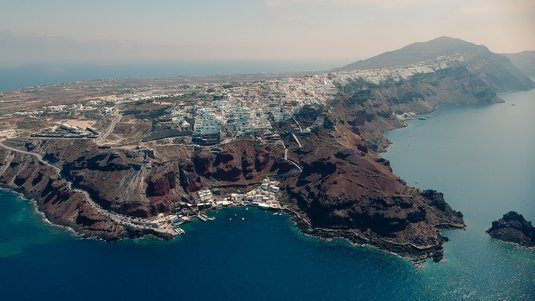 Luftaufnahme der Insel Santorin, mit einer engbebauten und felsigen Küste