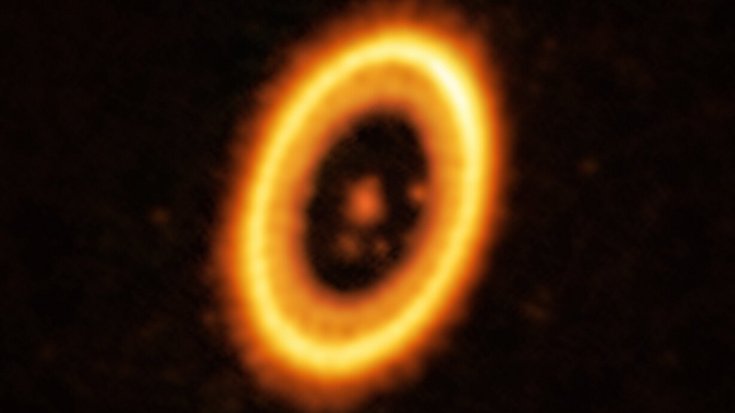 Leuchtendes Zentrum mit umgebendem Leuchtring und zwei weiter innen liegenden rötlich leuchtenden Punkten, die gleich weit vom Zentrum des Rings entfernt sind.
