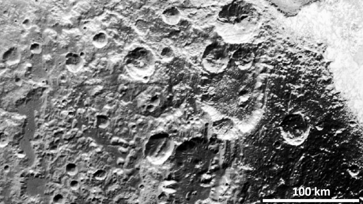 Schwarz-weiß-Aufnahme des Pluto, auf dessen Oberfläche einige Krater zu sehen sind