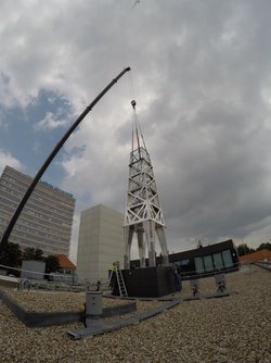 Bau an der Atomfontäne in Hannover. Das 15 Meter hohe Gerüst wird mit einem Kran aufgebaut und erinnert an einen Turm. Im Hintergrund befindet sich die Universität Hannover.