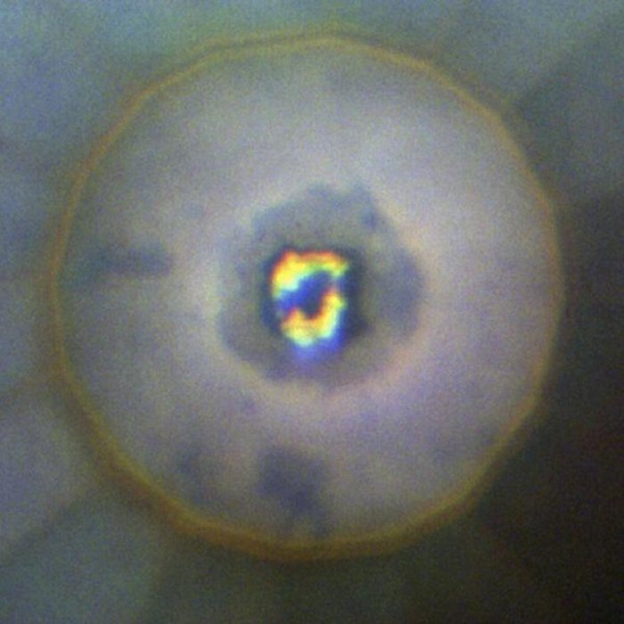 Iridiumhydrid In der Mitte einer kreisförmigen Blase befindet sich eine dunkle Region aus Iridiumhydrid, die mit hellen Flecken aus Wasserstoff durchsetzt ist.