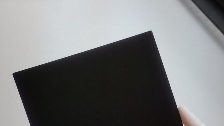 Solarzelle in Form eines schwarzen Quadrats in behandschuhten Händen