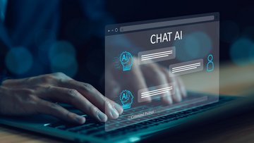 Eine Person tippt auf der Tastatur eines Laptops mit holografischer Benutzeroberfläche, die einen KI-Chat zeigt. Im oberen Bereich der holografischen Benutzeroberfläche steht „Chat AI“.
