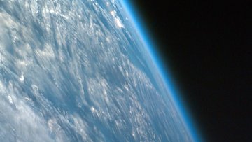 Schräger Blick auf die Erde aus dem Weltraum, die Atmosphäre leuchtet.