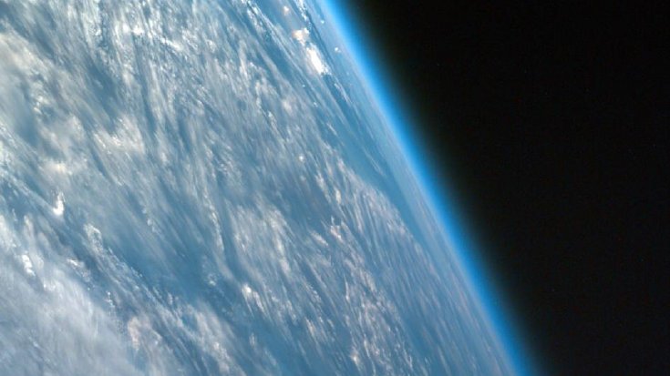 Schräger Blick auf die Erde aus dem Weltraum, die Atmosphäre leuchtet.