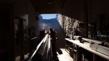 Zwei Männer in Polarkleidung arbeiten an einem Eisbohrkern.