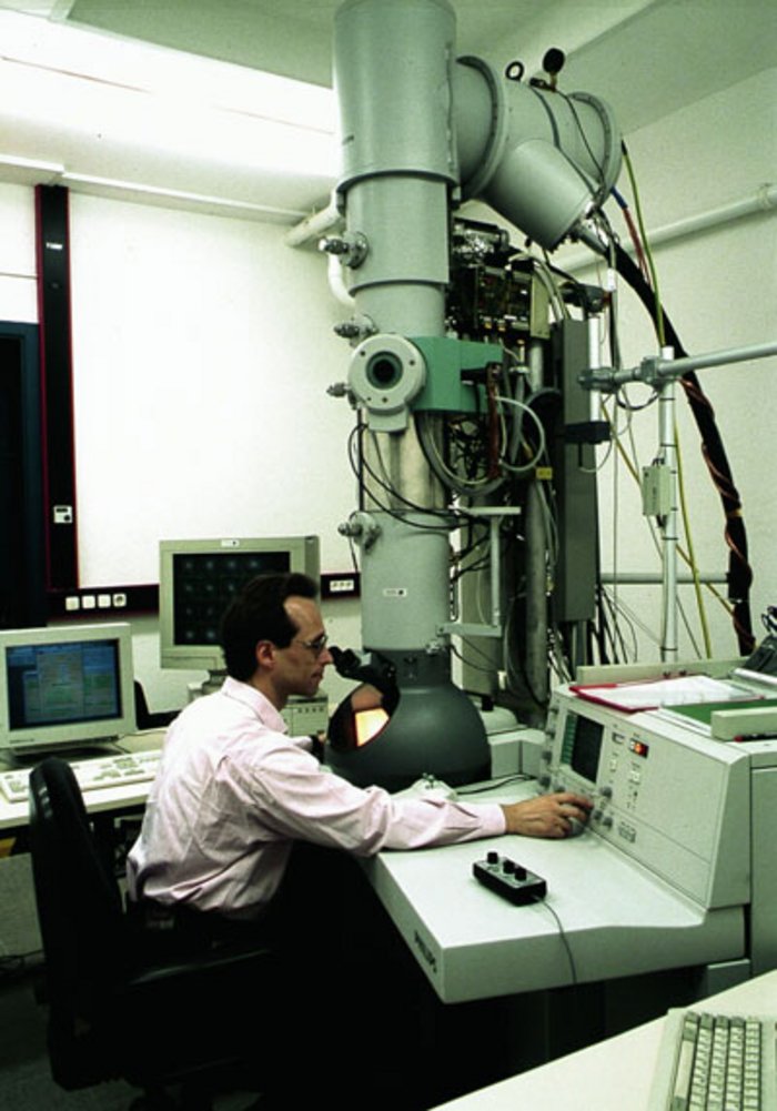 Bild 6: Arbeitsplatz Elektronenmikroskop Mann schaut in das Okular eines Elektronenmikroskops
