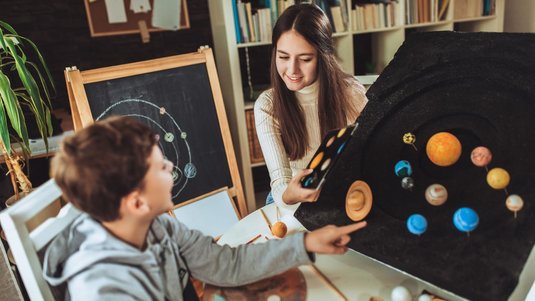 Zwei Kinder fertigen am heimischen Schreibtisch ein Modell unseres Sonnensystems