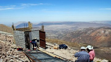 Bauarbeiter errichten eine geoynamische Beobachtungsstation auf einer Anhöhe im Gebirge.