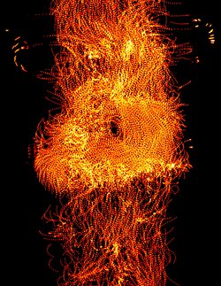 Orangerot leuchtende Ketten aus winzigen Mikrokugeln formieren sich zu einem Schwarm, der sich vor dunklem Hintergrund in eine Richtung bewegt.