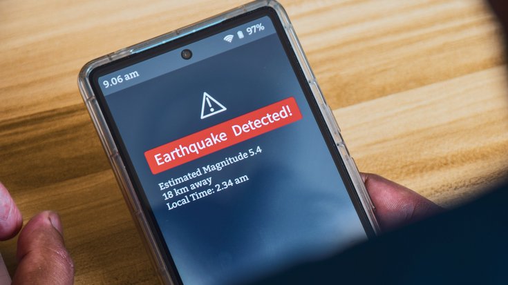 Erbebenwarnung auf dem Smartphone | Bildquelle: Debalina Ghosh/iStock Eine Hand hält ein Smartphone, auf dem eine Erdbebenwarnung erscheint. Darauf steht: Earthquake Detected! Estimated Magnitude: 5,4. 18 km away. Local Time: 2:34 am.