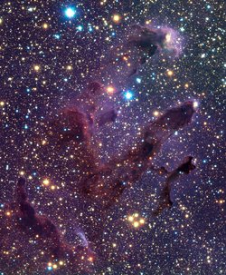 Himmelsfeld voller Sterne; von links unten nach rechts oben zeichnen sich parallel drei dunkle Gassäulen wie Finger ab.