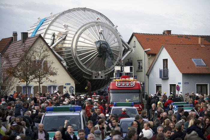 2006 wurde das Spektrometer für KATRIN an das Karlsruher Institut für Technologie gebracht – und brauchte für den Weg von Deggendorf nach Karlsruhe rund 8600 Kilometer meist auf dem Seeweg. Ein Transport über Land war aufgrund der Größe des Spektrometers nicht möglich. Die letzten paar Kilometer legte KATRIN dann auf einem Schwertransport zurück, auf dem Bild zu sehen ist der Weg des Spektrometers durch den Ort Leopoldshafen, bei dem KATRIN genau zwischen zwei Häuser zu passen scheint.