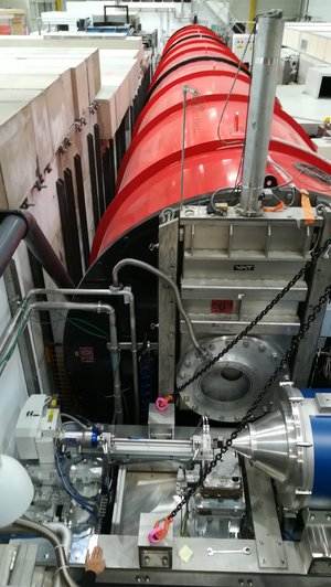 Das Bild zeigt das neue Instrument, an dem noch Ketten für den Kran befestigt sind, mit dem es in die Probenumgebung gebracht wurde. Hinter der Spitze des Instruments ist das große rote Detektorrohr zu sehen.