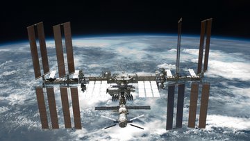 Das Experiment AMS-02 ist im Weltall zu sehen, im Hintergrund die Erde.
