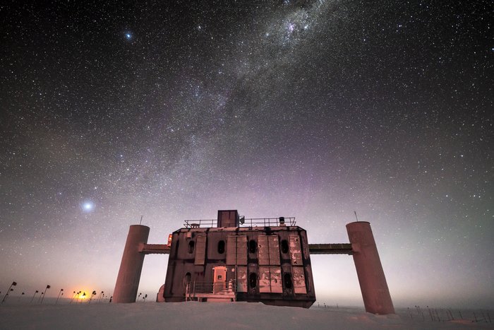 Das IceCube-Observatorium Laborgebäude auf schneebedeckter Fläche unter einem Sternenhimmel.