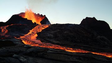 Aus einem Vulkan schießt glühende Lava und fließt den Vulkan herab