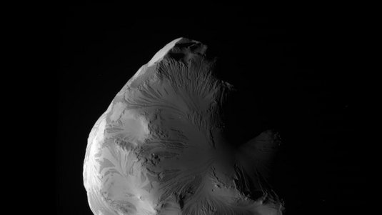 Eisbedeckter, asymmetrischer Saturnmond vor dunklem Hintergrund