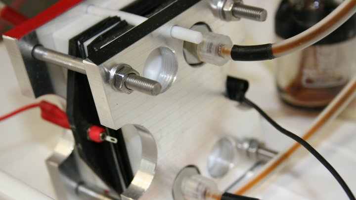 Mit Kabeln angeschlossene Flüssigbatterie, die von zwei Metallplättchen ummantelt ist.