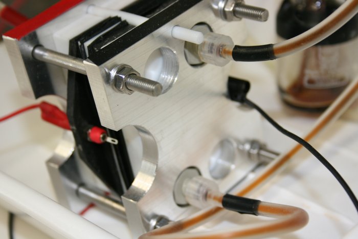 Günstige Flüssigbatterie Mit Kabeln angeschlossene Flüssigbatterie, die von zwei Metallplättchen ummantelt ist.