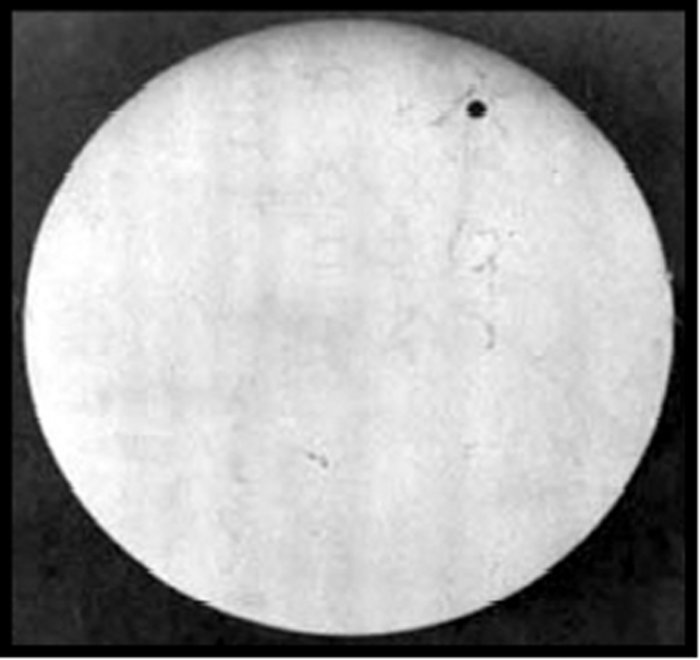 Venustransit 1882 Schwarz-weiß-Foto eines hellen Himmelskörper, in dessen oberen Bereich sich ein kleiner schwarzer Kreis zeigt