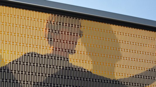 Ein Mensch hält ein großes Solarmodul mit beiden Armen in die Sonne.