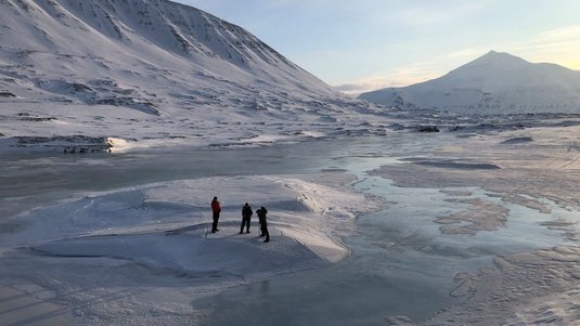 Drei Menschen auf einer schmelzenden Gletscherfläche