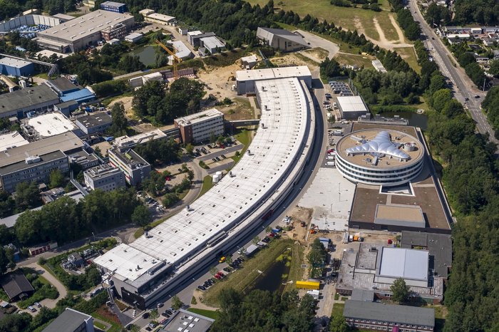 Die Max-von-Laue-Halle an PETRA III bei DESY in Hamburg Ein zwei Stockwerke hohes, langes und leicht gebogenes Gebäude auf einem Luftbild.