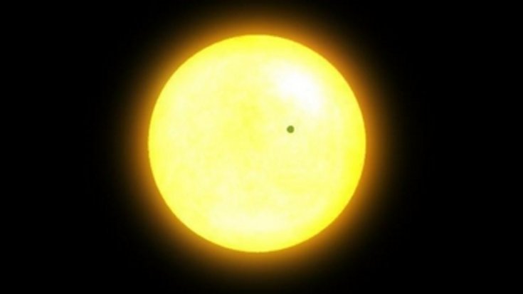 Eine hell leuchtende Sonne, vor der ein Planet als kleiner, dunkler Punkt vorbeizieht.