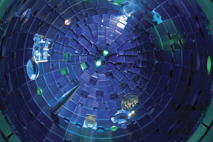 Die Targetkammer der National Ignition Facility Blick in eine kuppelförmige Kammer, durch die Wand links unten ragt ein Kegel aus Metall hinein, der nach vorne stark zugespitzt ist.