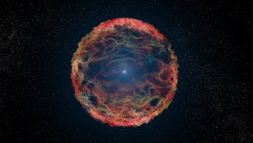 Im Zentrum der Abbildung leuchtet ein heller Punkt, der von farbigen Gasstrukturen umgeben ist. Die Gaswolken bilden eine unregelmäßige, runde Form, die aus leuchtenden Filamenten besteht.