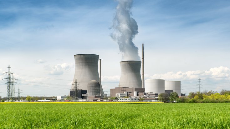 Das Bild zeigt ein aktives Atomkraftwerk und eine grüne Wiese.