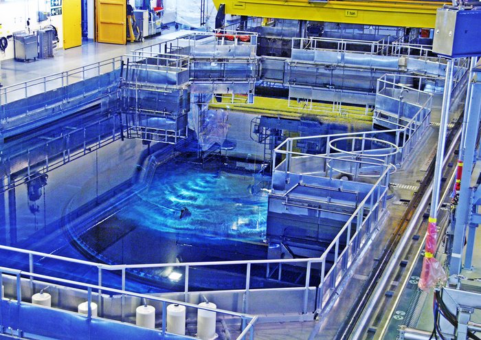 Blau schimmerndes Wasserbecken mit Gerüsten drumherum, im Inneren einer Maschinenhalle