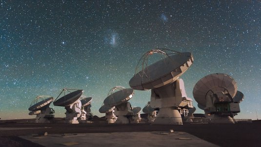Vor dem nächtlichen Himmel ist ein Teil des Teleskopverbunds ALMA zu sehen.