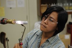 Doktorandin Marianne Tarun bei der Arbeit. Mit einem Brenner in der Hand erhitzt sie ein Material.