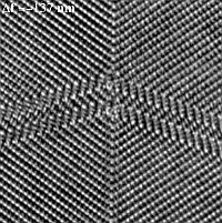 Kristallatome streng als weiße Punkte auf schwarzer Fläche angeordnet, Struktur pfeilförmig zugespitzt